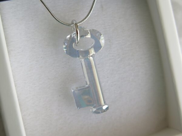 Ogrlica od Swarovski Elemenata s privjeskom u obliku ključa. Kristal je proziran s plavo - sivim odsjajem.